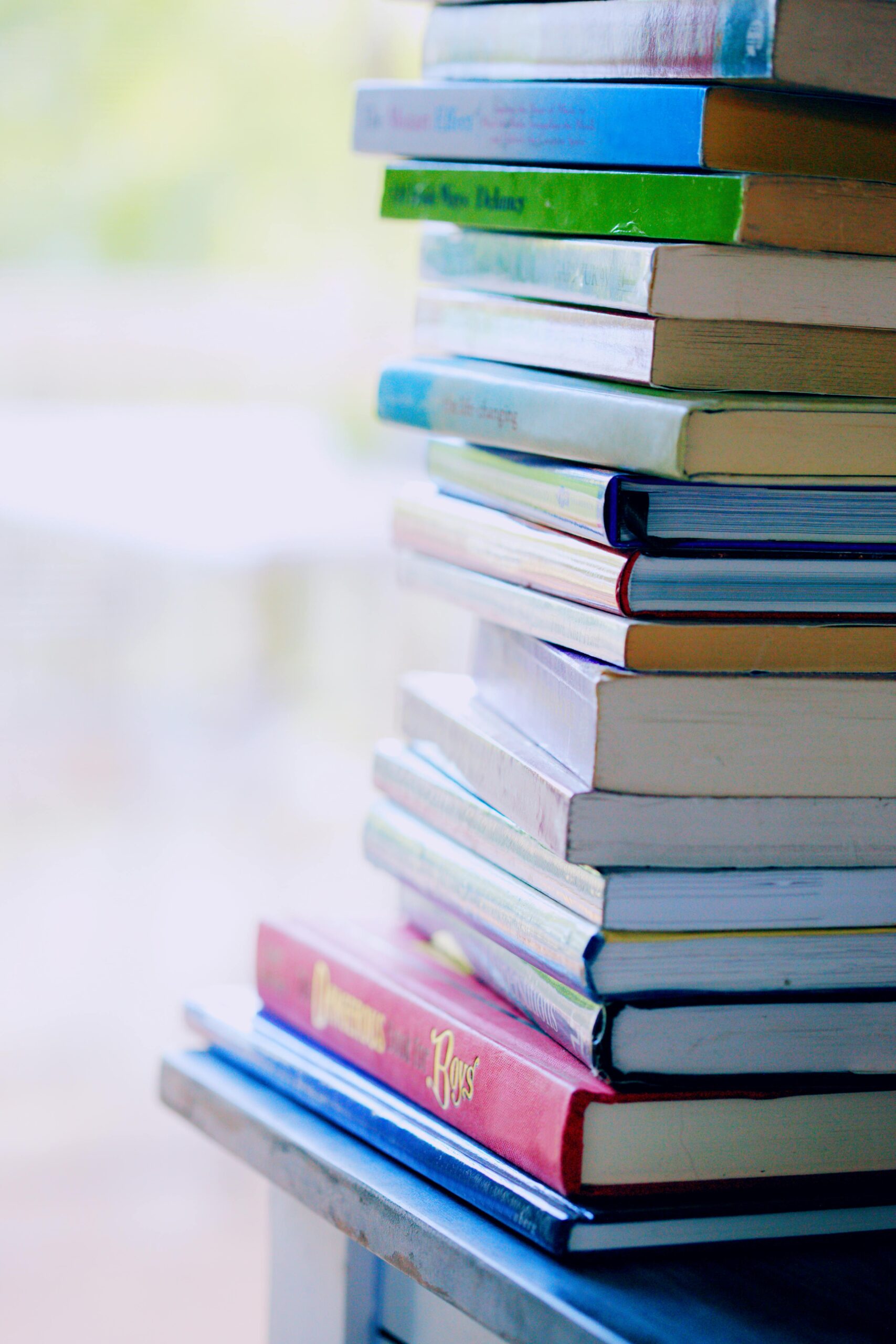 A tall stack of colorful hardcover books on a table indoors, perfect for library-themed concepts.